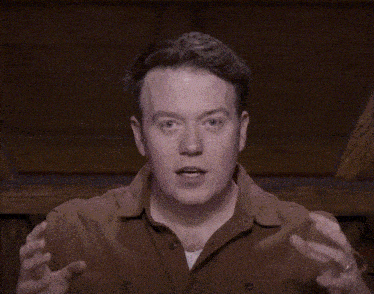 a man is covering his face with his hands and looking at the camera