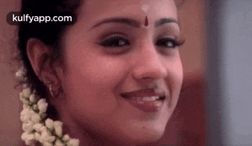 a close up of a woman 's face with a flower in her hair and a bindi on her forehead .