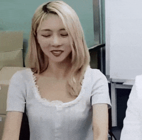 a woman with blonde hair is sitting at a table with her eyes closed and smiling .