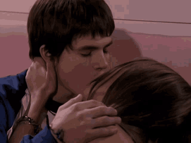 a boy and a girl kissing on a pink couch