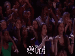 a crowd of people are sitting in a stadium watching a concert and taking pictures with their phones .