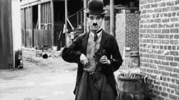 a black and white photo of a man in a suit and hat .