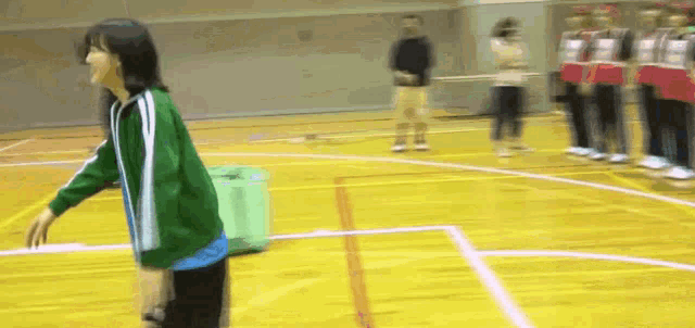 a girl in a green jacket is standing on a basketball court