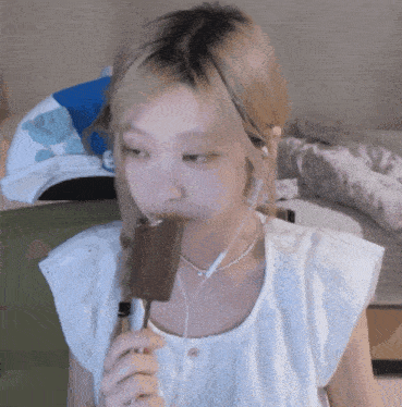 a woman wearing earbuds is eating a chocolate bar