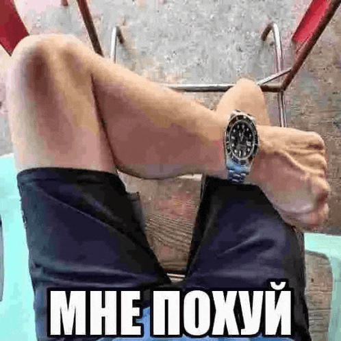a man is sitting on a chair with his legs crossed and wearing a watch .