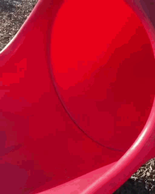 a shirtless man sits on a red slide wearing a black hat