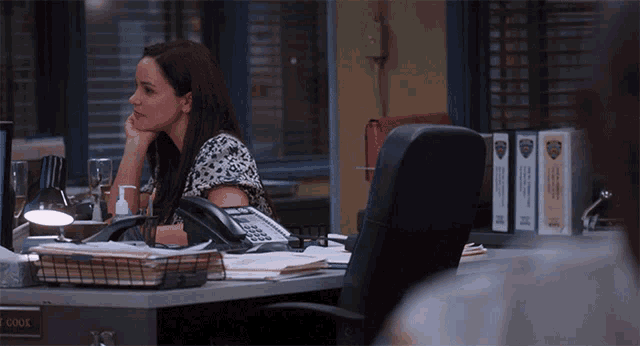 a woman sits at a desk with a name tag that says t cook