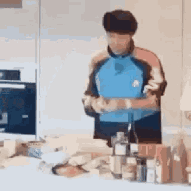 a man in a blue shirt is standing in front of a kitchen counter .