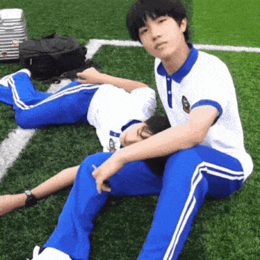 a boy sits next to a girl who is laying on the grass with the letter a on her shirt