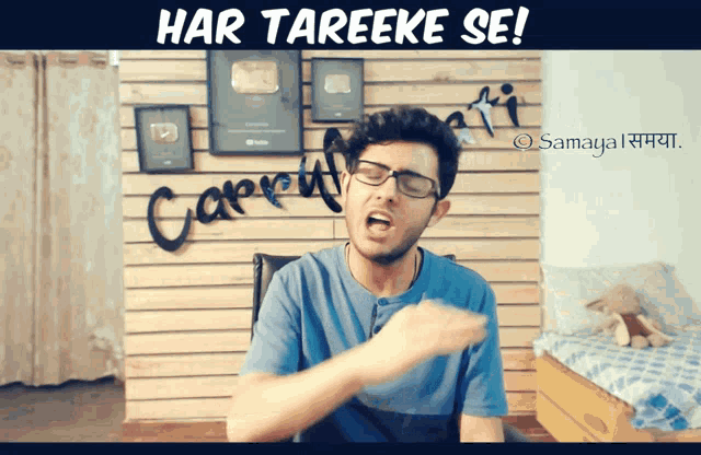 a man wearing glasses is making a funny face in front of a wall that says " har tareeke se "