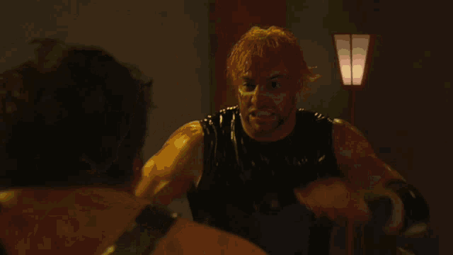 a man with red hair in a black tank top is fighting another man