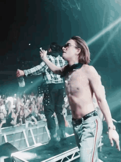 a shirtless man is standing on a stage holding a bottle of alcohol
