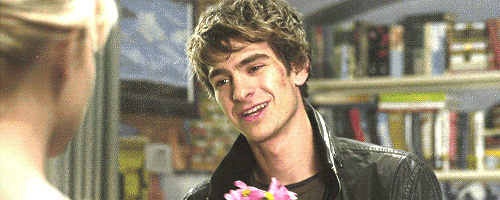 a man in a leather jacket is smiling while holding a pink flower