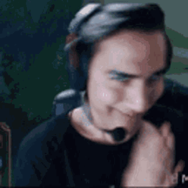 a man wearing headphones and a microphone is sitting in front of a computer monitor .