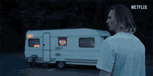 a man standing in front of a trailer that says netflix on the bottom right
