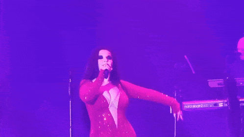 a woman in a red dress singing into a microphone in front of a nord stage 3 keyboard