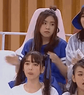 a group of girls are sitting in a stadium watching a game and one of them is wearing a blue shirt .