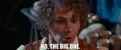 a man with curly hair is standing in a dark room and says `` no , the big one . ''