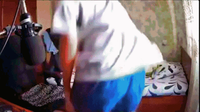 a person in a white shirt and blue shorts is standing in front of a microphone in a room .