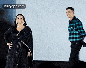 a woman in a black dress and a man in a plaid shirt are standing next to each other on a stage .
