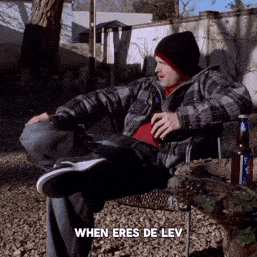 a man in a plaid shirt sits in a chair with a bottle of beer and the words when eres de lev above him