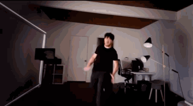 a man in a black shirt is standing in a dark room