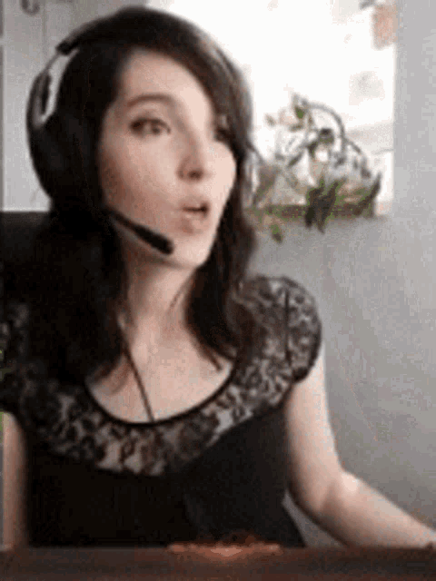 a woman wearing headphones and a microphone is sitting at a desk .