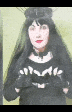 a woman in a black dress with a veil and gloves is making a heart shape with her hands