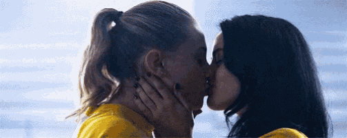 two women are kissing each other in a room .