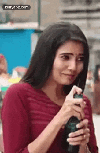a woman in a red shirt is holding a spray bottle in her hand and making a funny face .