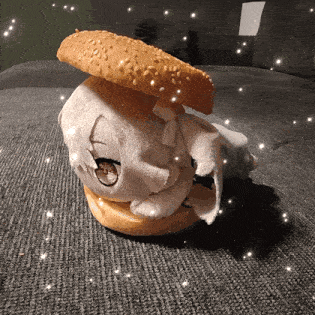 a stuffed animal is sitting on a couch with a hamburger on top