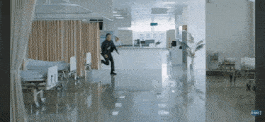 a man is running through a hospital hallway with a sign that says gmm