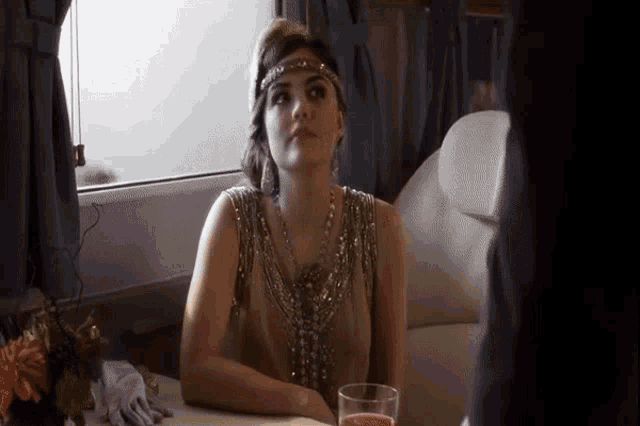 a woman in a flapper dress is sitting at a table with a glass of wine