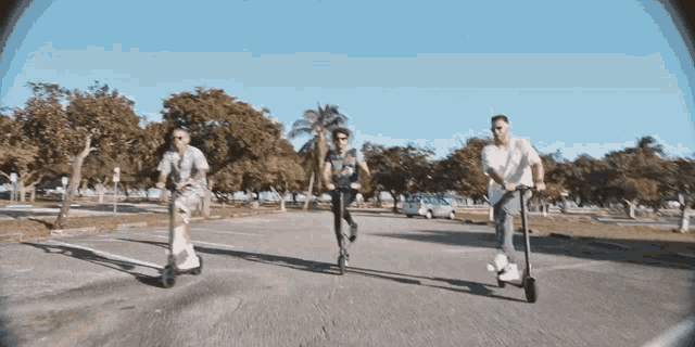 a group of people are riding scooters down a street