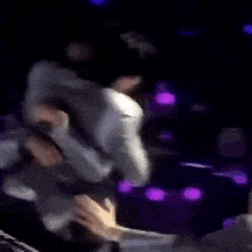 a man is hugging another man in a dark room .