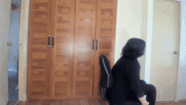 a blurry picture of a person sitting in a chair in front of a closet