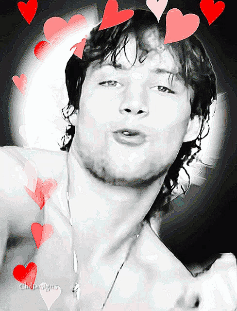 a black and white photo of a shirtless man with hearts around his face