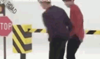 two people are standing in front of a stop sign