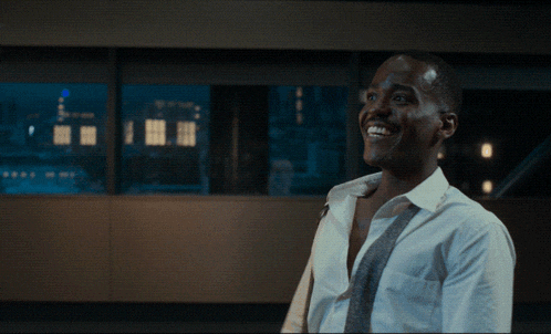 a man in a white shirt and tie is smiling in front of a window with the words ta da !!! written above him