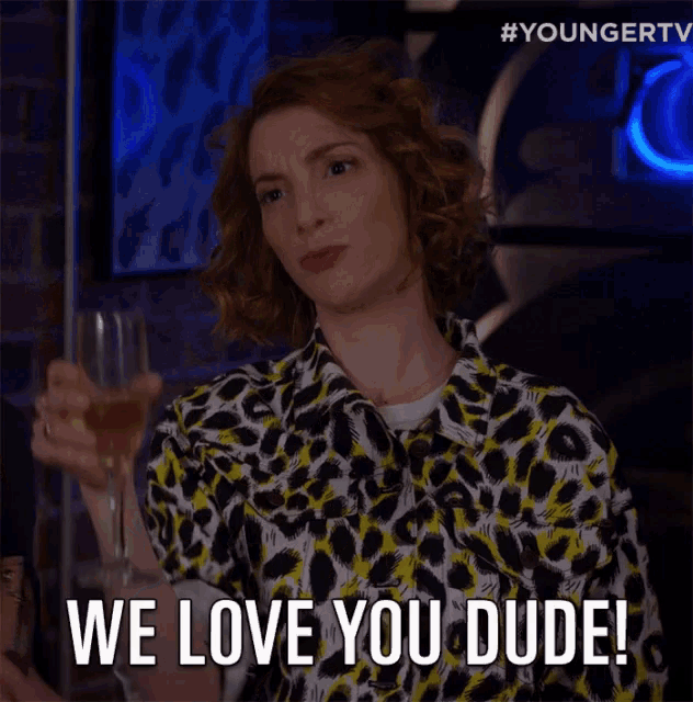 a woman in a leopard print shirt holds a glass of wine and says " we love you dude "
