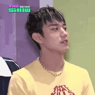 a young man wearing a yellow shirt and a necklace .