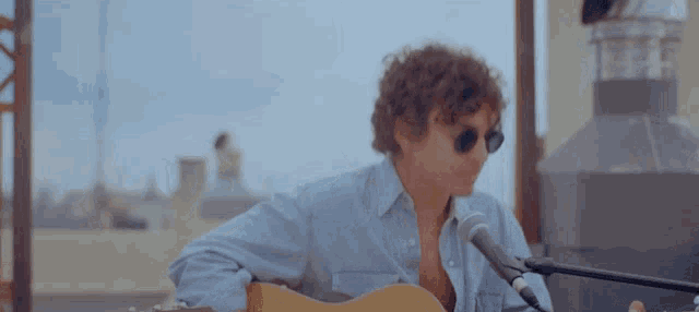 a man singing into a microphone while holding a guitar