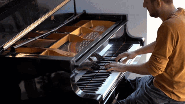 a man playing a piano with the lid open