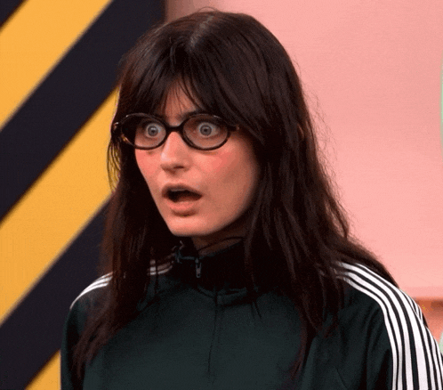 a woman wearing glasses and a green jacket is making a surprised face