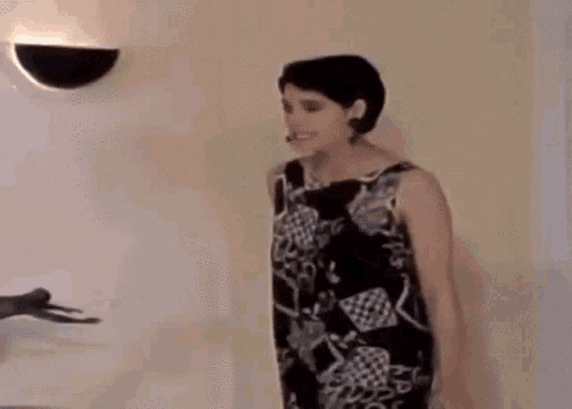 a woman in a black and white dress is standing in a room with her arms outstretched .
