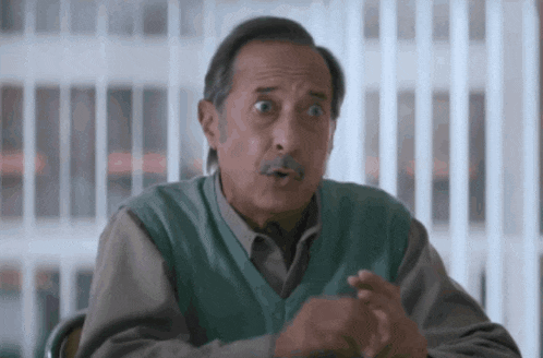 a man with a mustache is wearing a green sweater