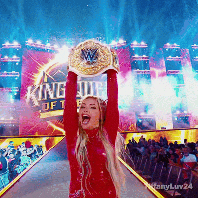 a woman in a red outfit is holding up a wrestling championship belt in front of a sign that says king of fighters