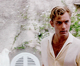 a man in a white shirt is standing in front of a white shutter