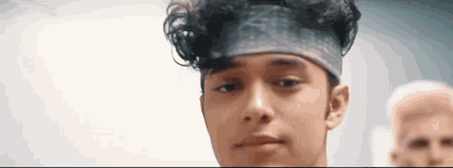 a young man wearing a headband looks at the camera .