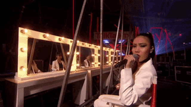 a woman is singing into a microphone in front of a sign that says tiki